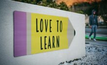 love to learn pencil signage on wall near walking man
